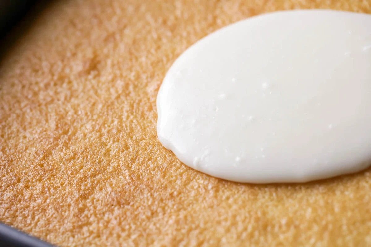 Frosting being spread over vanilla texas sheet cake