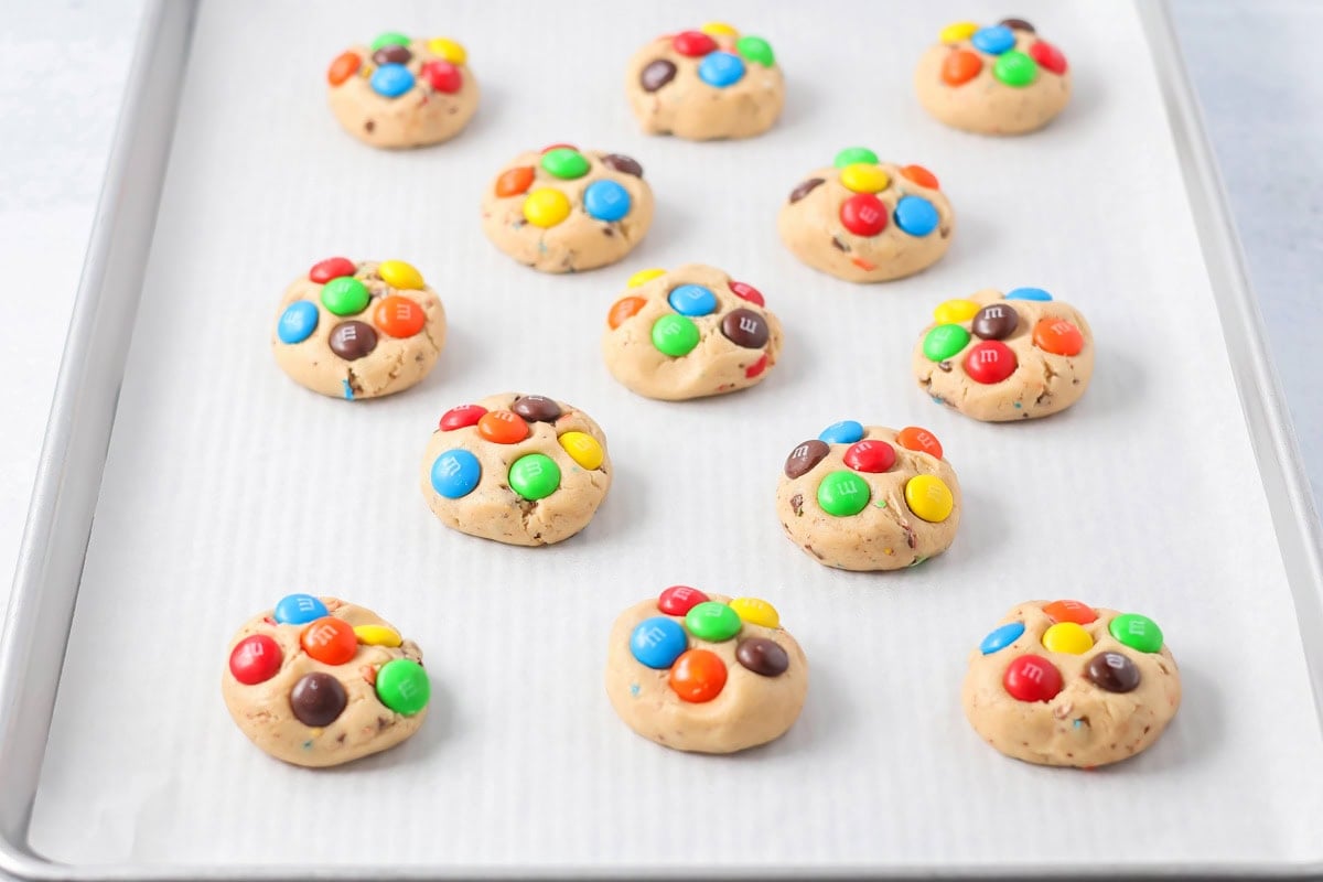 M&Ms on cookie dough on baking sheet.