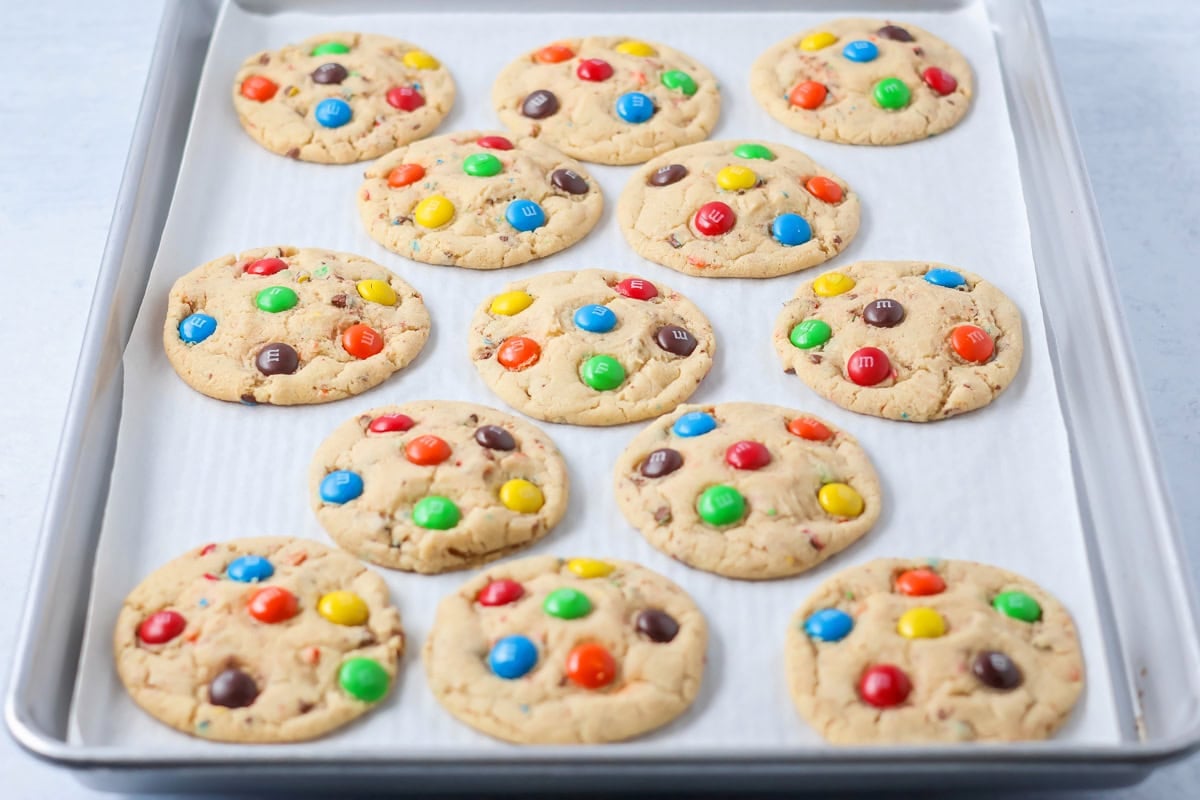 M&M cookies baked on baking sheet.