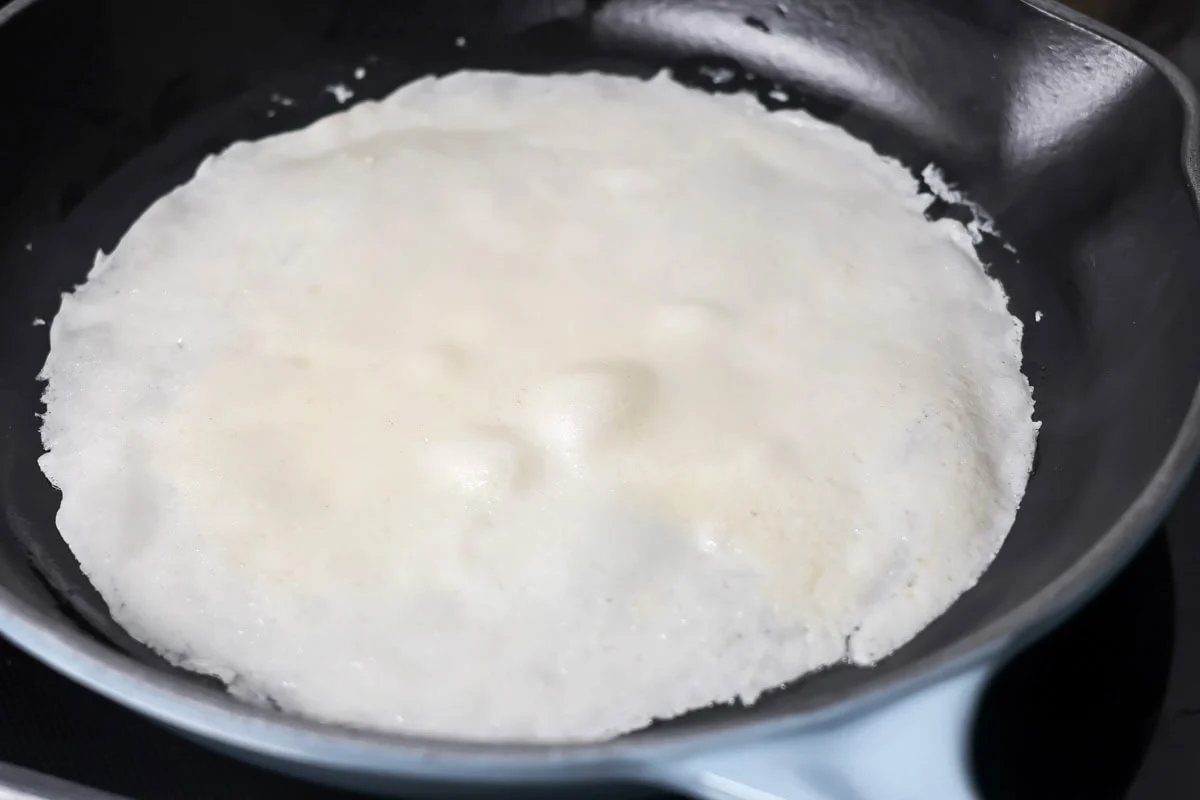 Swedish pancakes cooking in skillet.