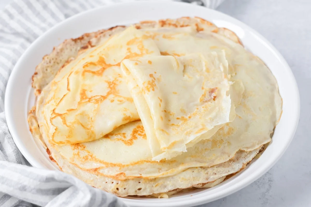 Swedish pancakes folded on white plate.