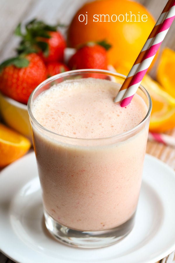 Orange juice smoothie in a glass cup with two straws