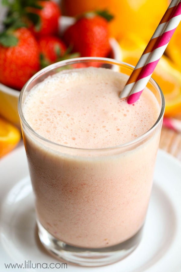 close up of orange juice smoothie in a glass cup on a white plate