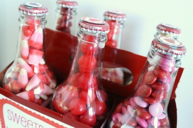 Candy filled and capped bottles placed in the red carton that has had Valentines Day printable labels applied.