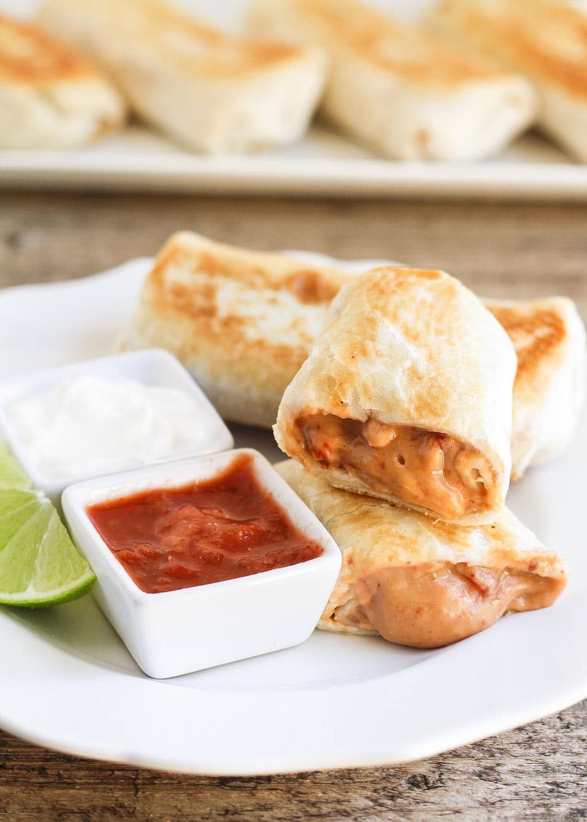 Bean and cheese chimichanga on a plate with salsa and sour cream