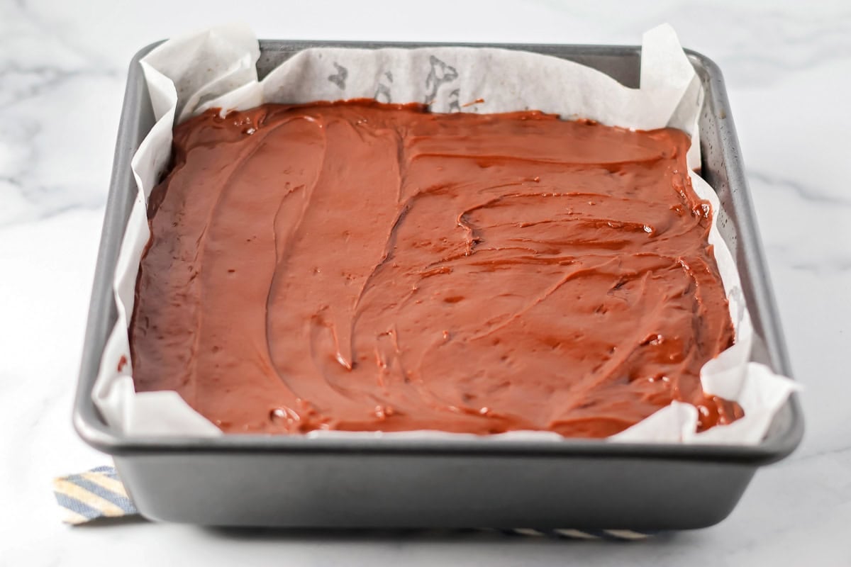 Spreading chocolate frosting on cooked brownies.