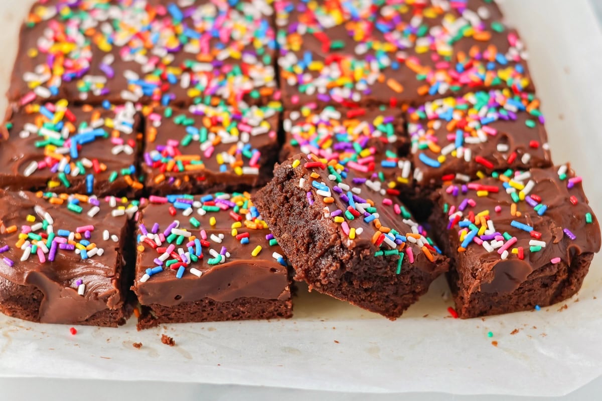 A close up of cut, frosted brownies topped with sprinkles.