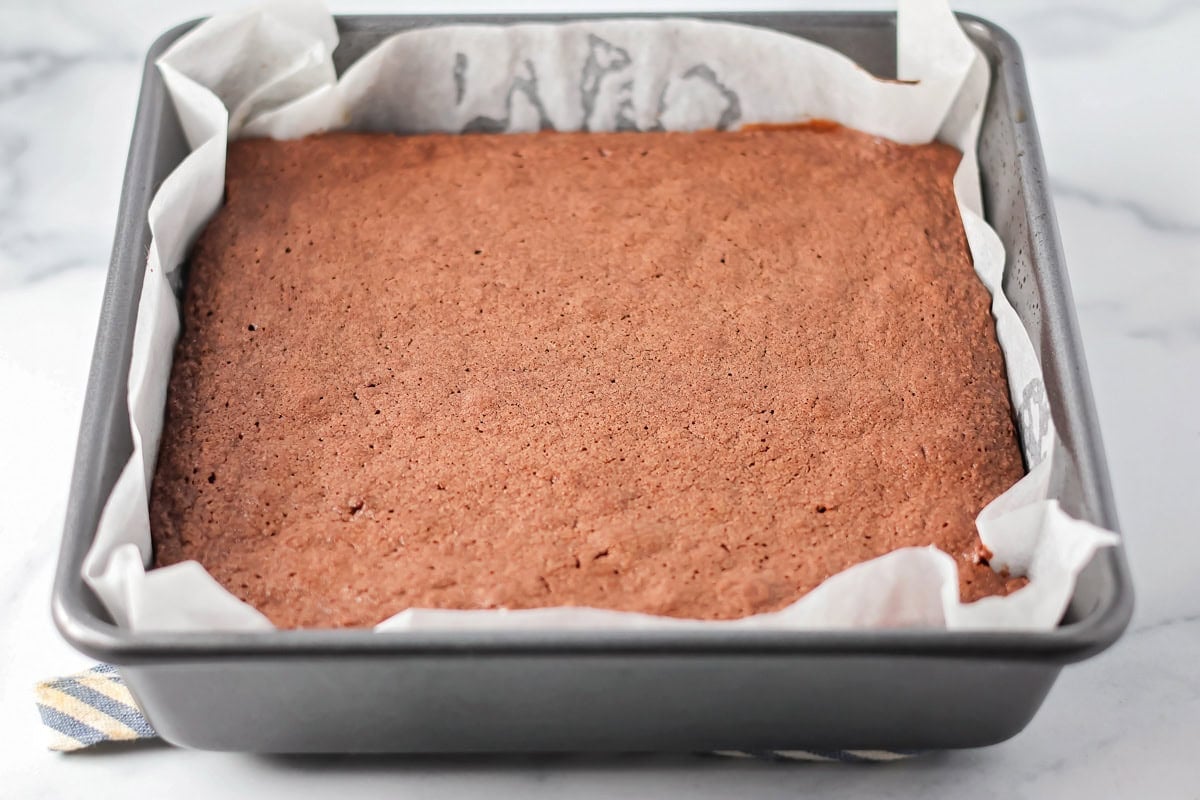Cooked brownies in a lined baking pan.
