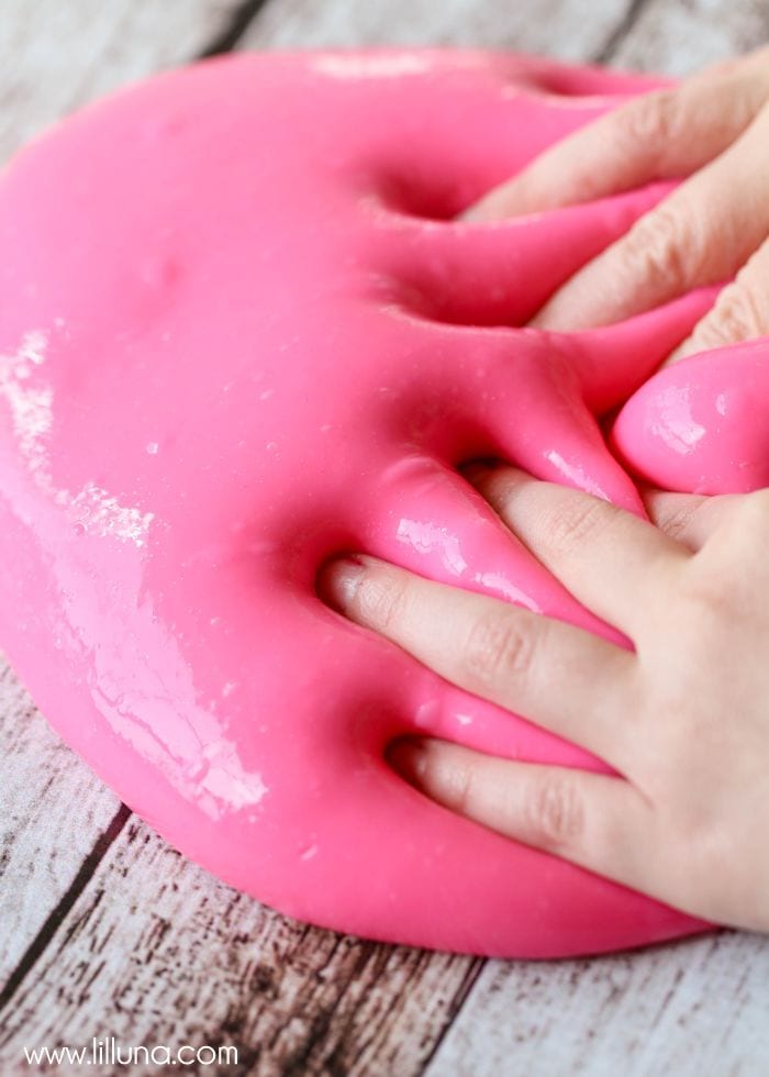 Two hands playing in pink gak