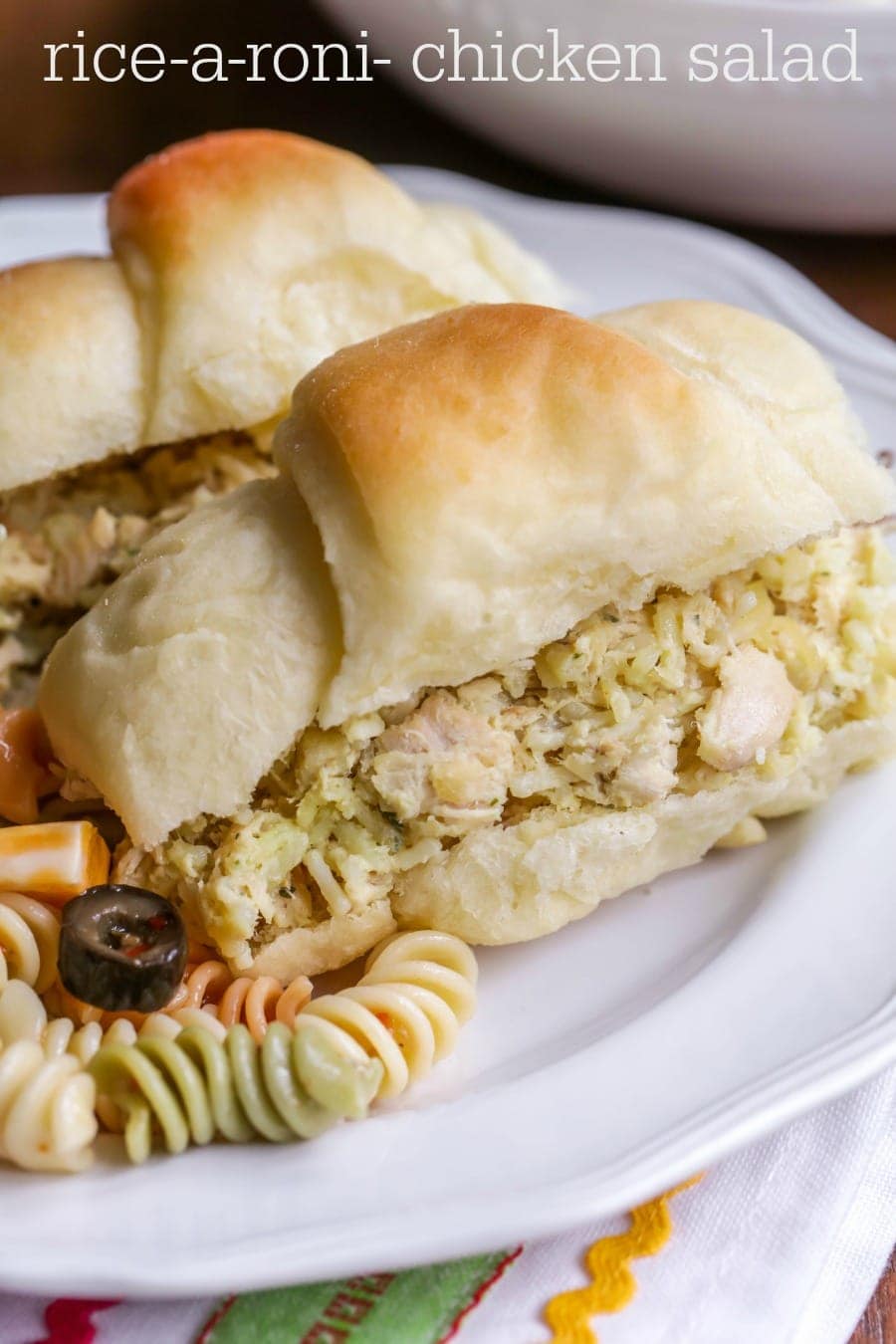 Rice-a-Roni Chicken Salad served in a homemade rolls alongside pasta salad on a white plate