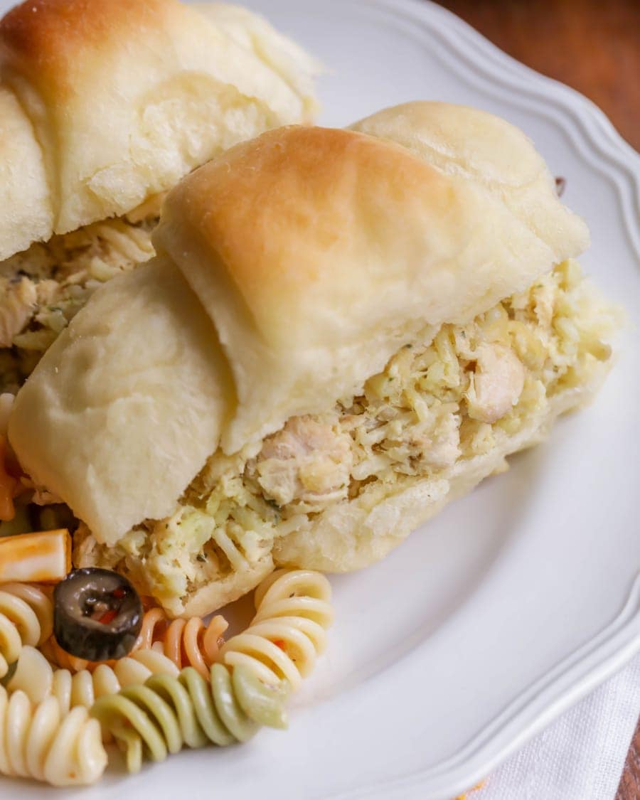 Close up of chicken salad served in a roll on a white plate