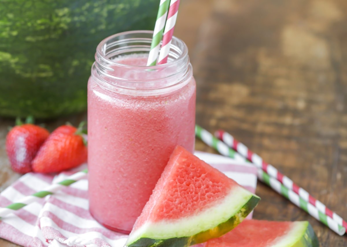 Watermelon juice in a glass jar with two striped straws. 