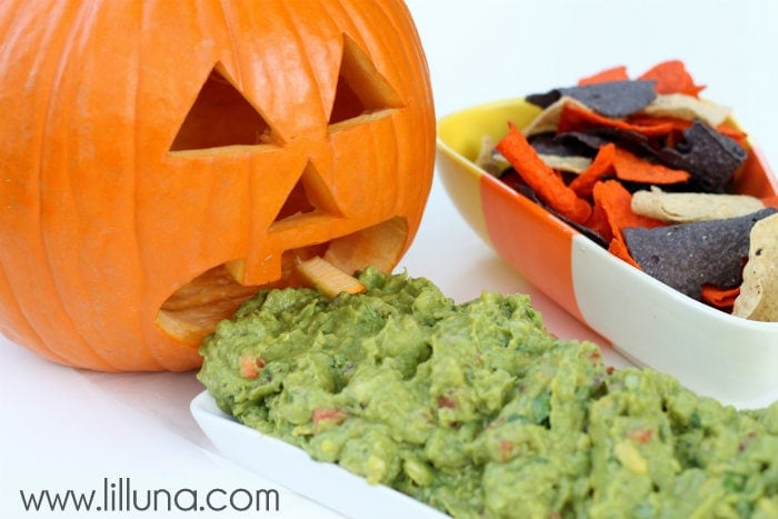 Barfing Pumpkin Guacamole on a white plate in front of a carved pumpkin