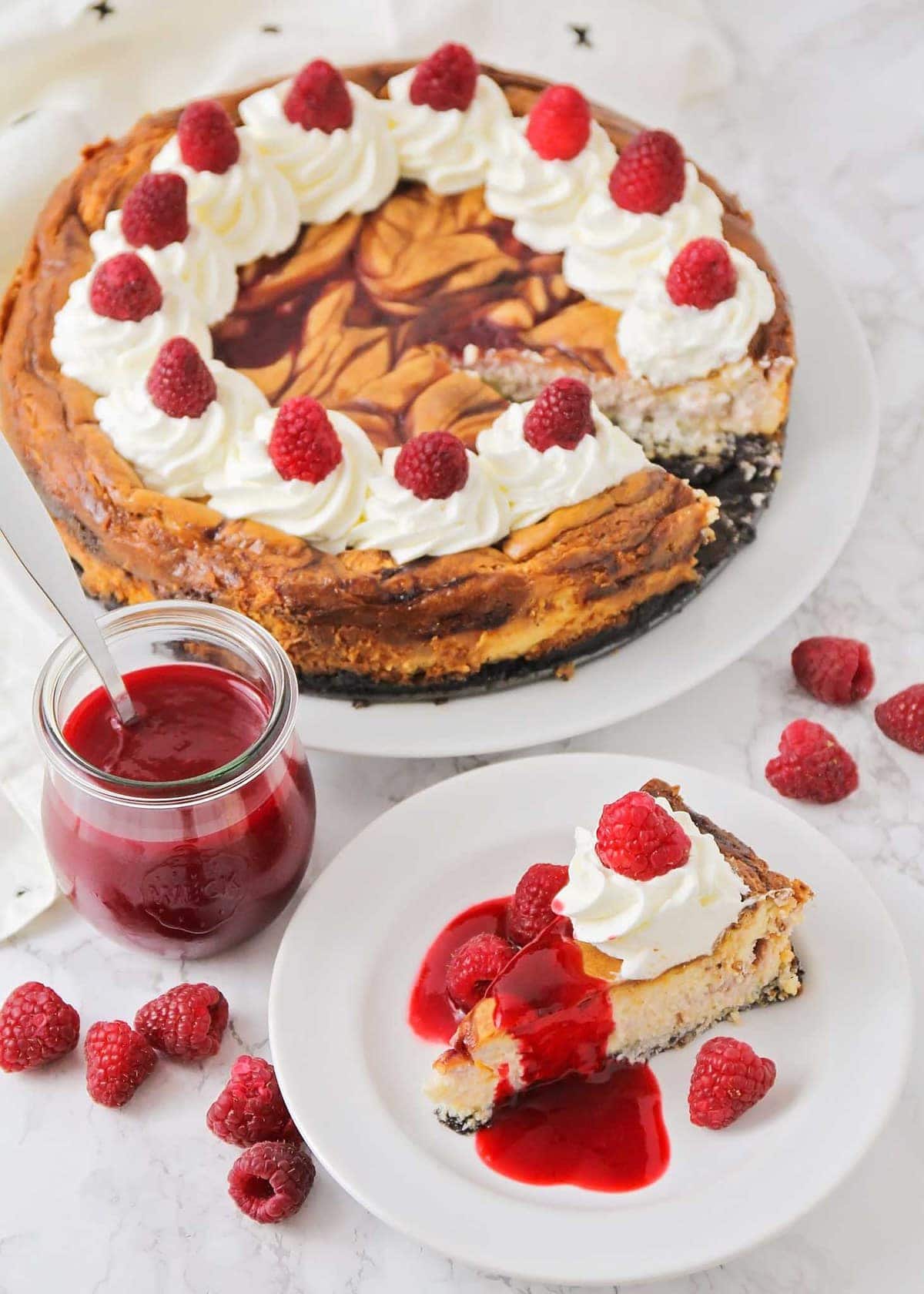 Cheesecake factory white chocolate raspberry cheesecake on a plate with whipped cream and fresh raspberries on top.