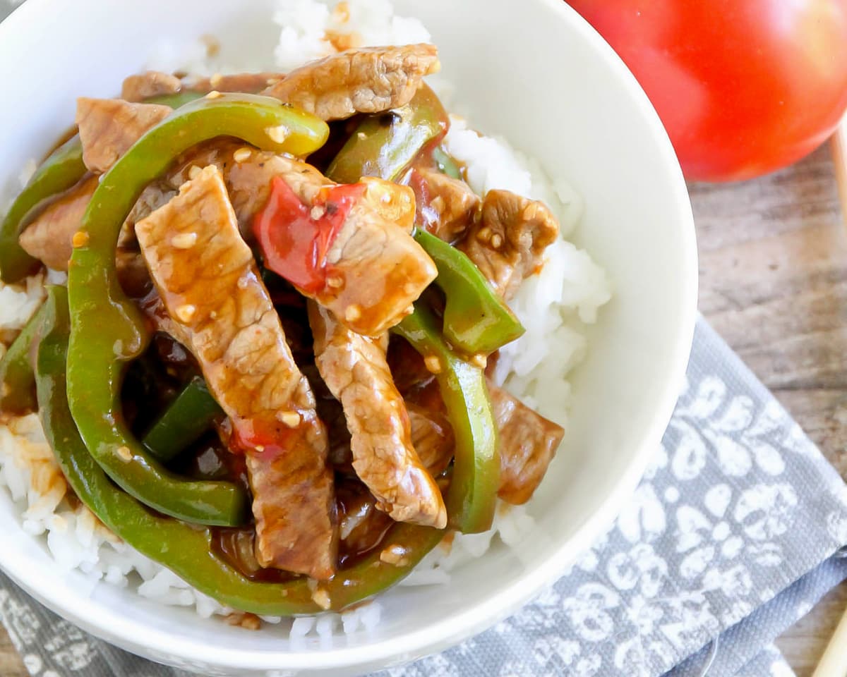 Pepper steak served over white rice with peppers in white bowl