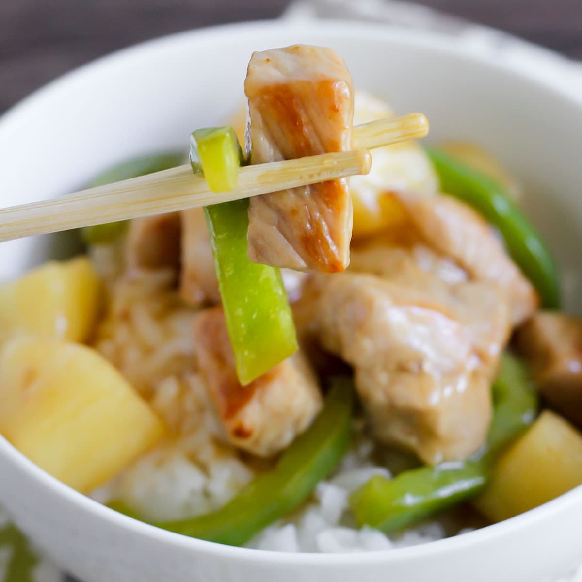 Asian Dinner Recipes - Sweet and sour pork on top of white rice in a white bowl. 