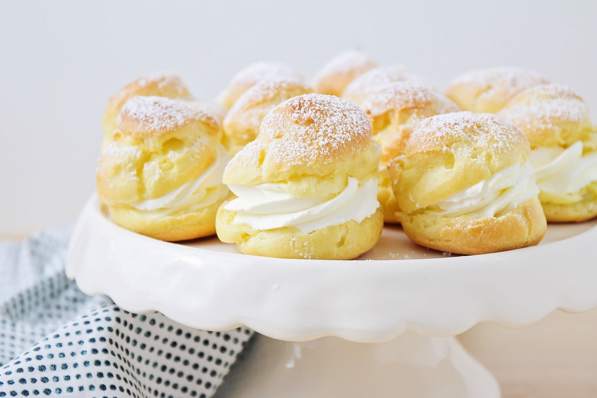 Homemade Cream Puffs served on a cake stand.