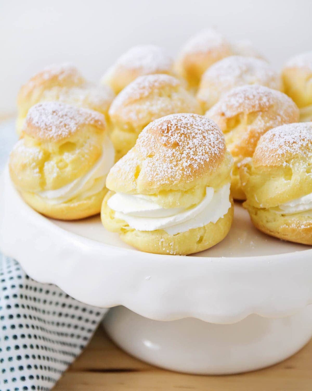 Mini cream puffs served on a white cake stand.