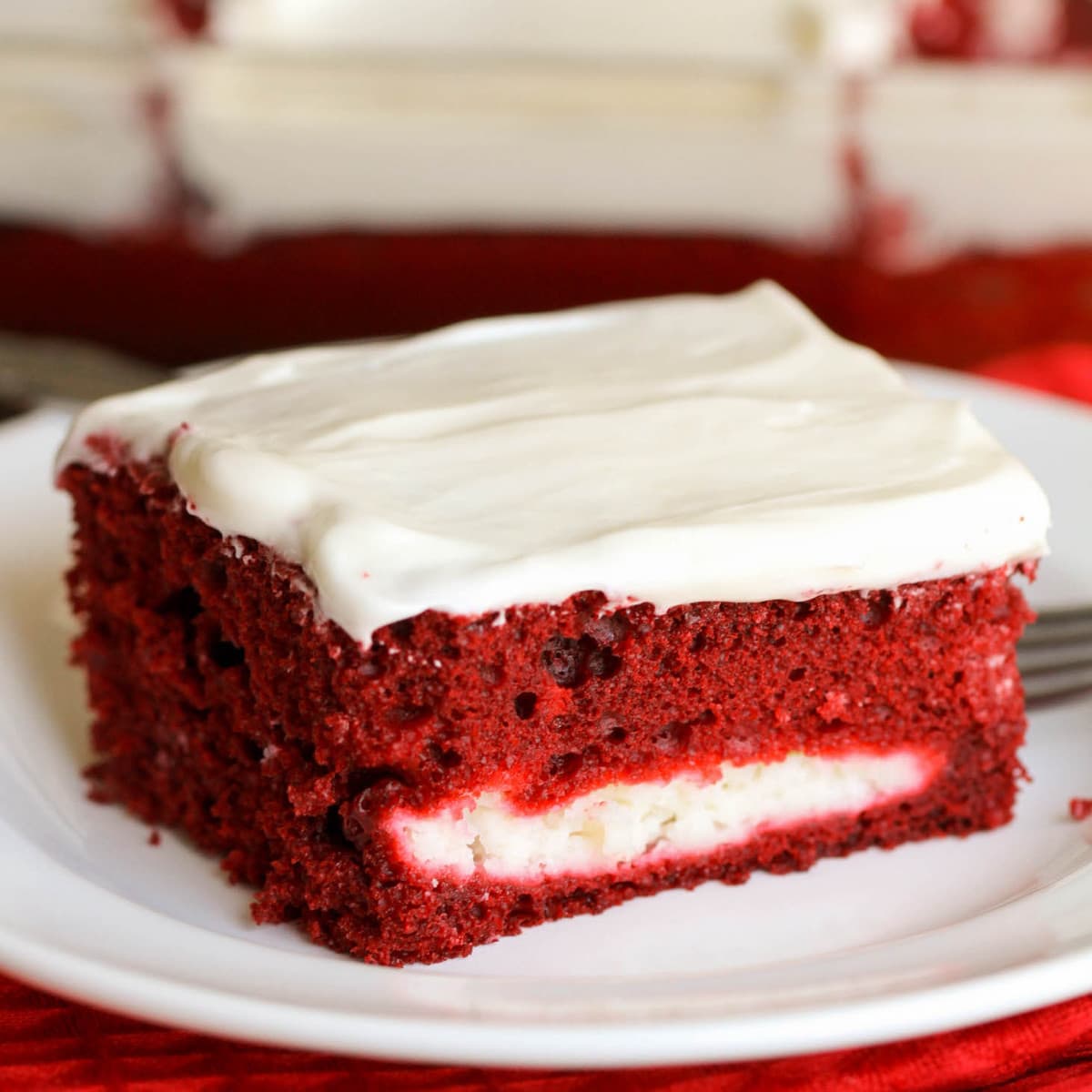 Valentine's Day Desserts - red velvet cheesecake cake with white frosting on a white plate. 