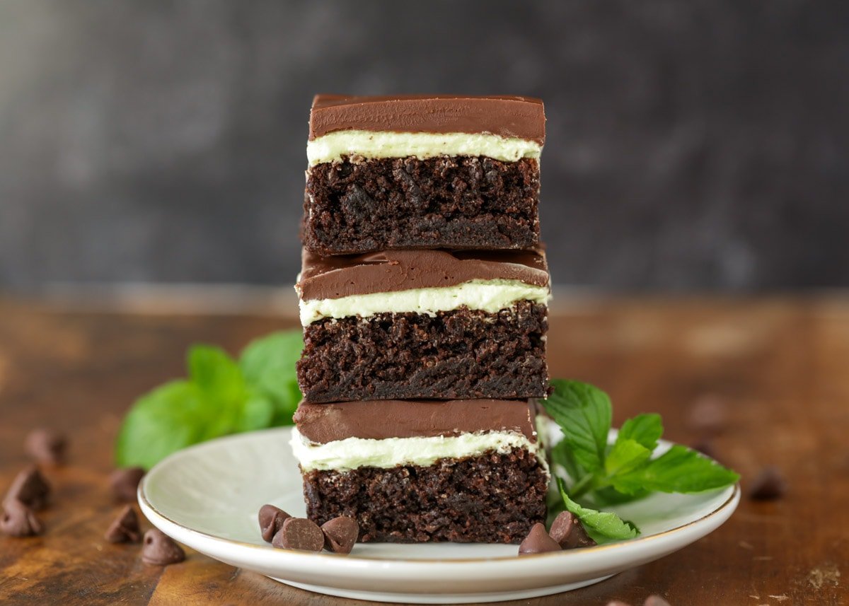 Three mint brownies stacked on a white plate.