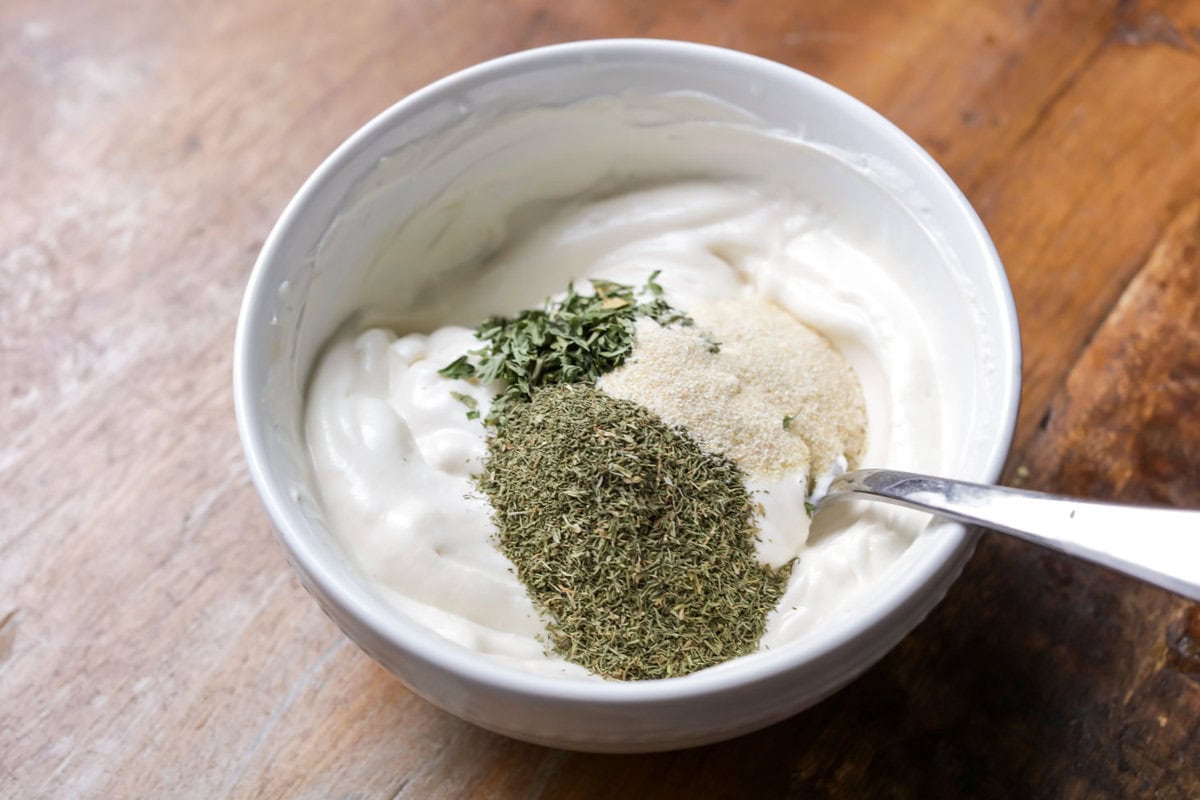 Adding spices to sour cream and mayonnaise mixture.