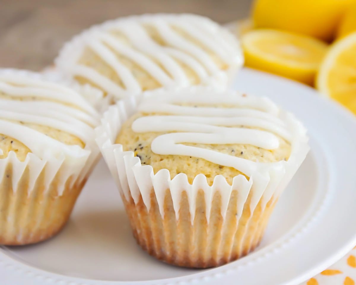 Muffin Recipes - Glazed lemon poppyseed muffins on a white plate.