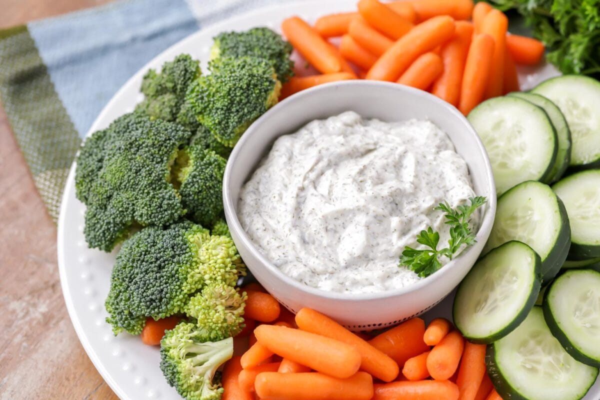 Our go-to veggie dip recipe in a white bowl with veggies all around it.