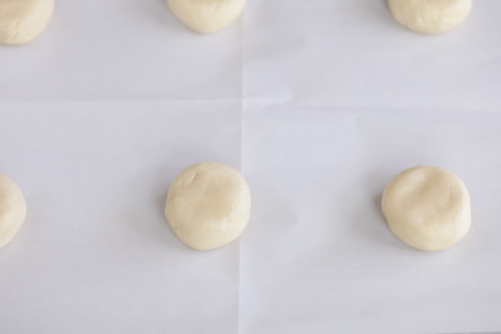 Balls of cookie dough on a parchment lined baking sheet