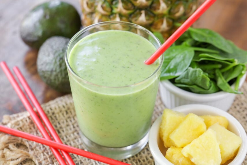 Fresh green smoothie served in a glass with a red straw