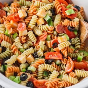 Pasta salad with Italian dressing mixed together in bowl.