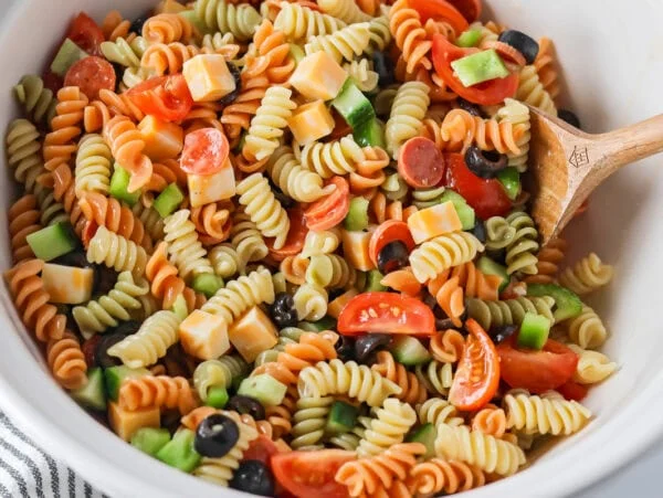 Pasta salad with Italian dressing mixed together in bowl.
