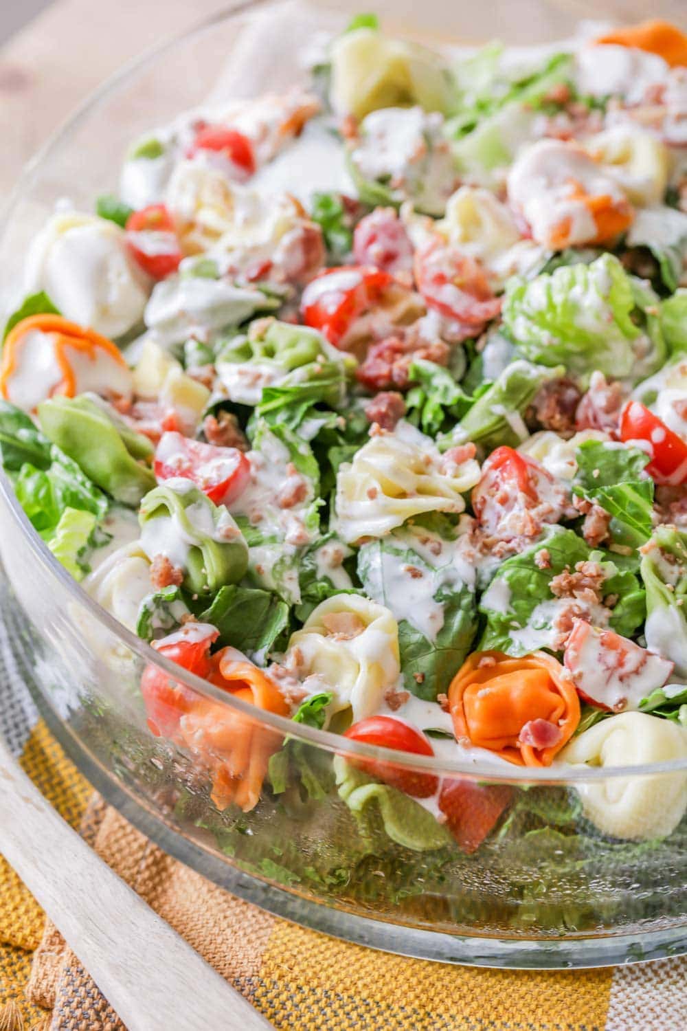 A close up of a glass bowl filled with tortellini salad.