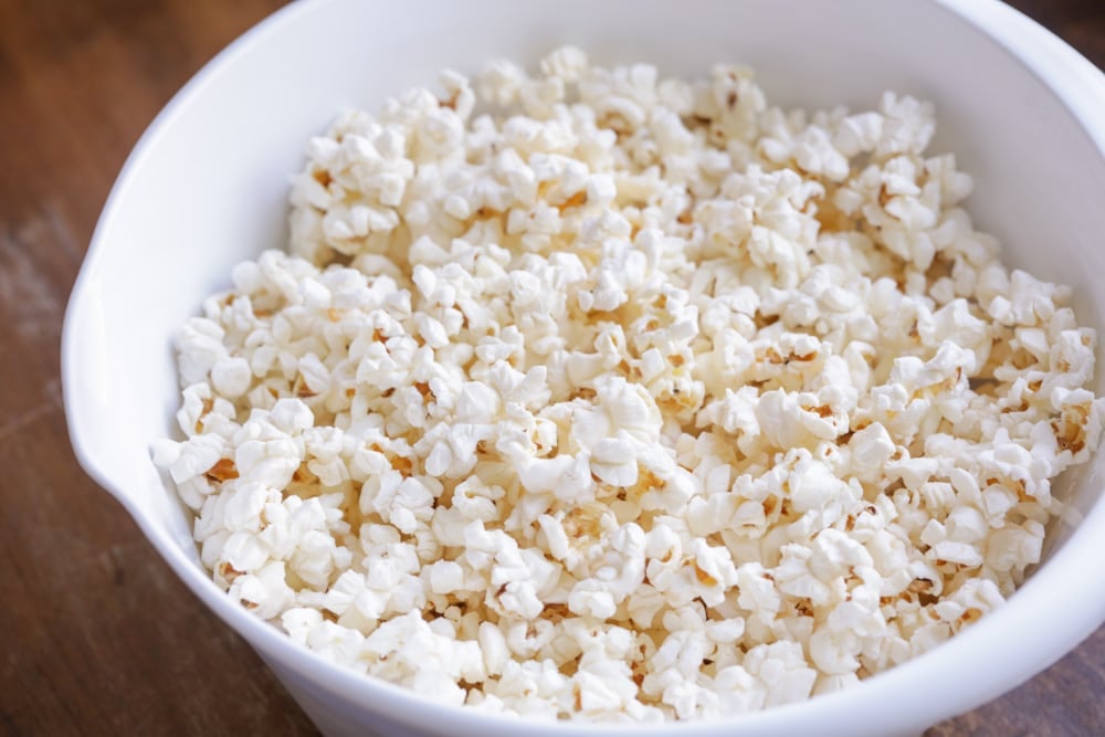 A white bowl of popped popcorn.