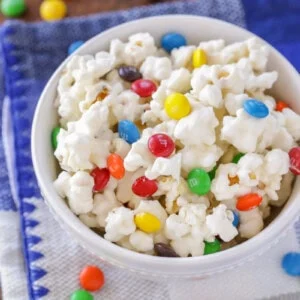 White chocolate popcorn with M&Ms in white bowl.