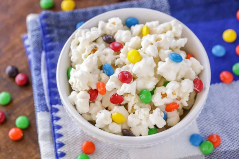 White chocolate popcorn with M&Ms in white bowl.