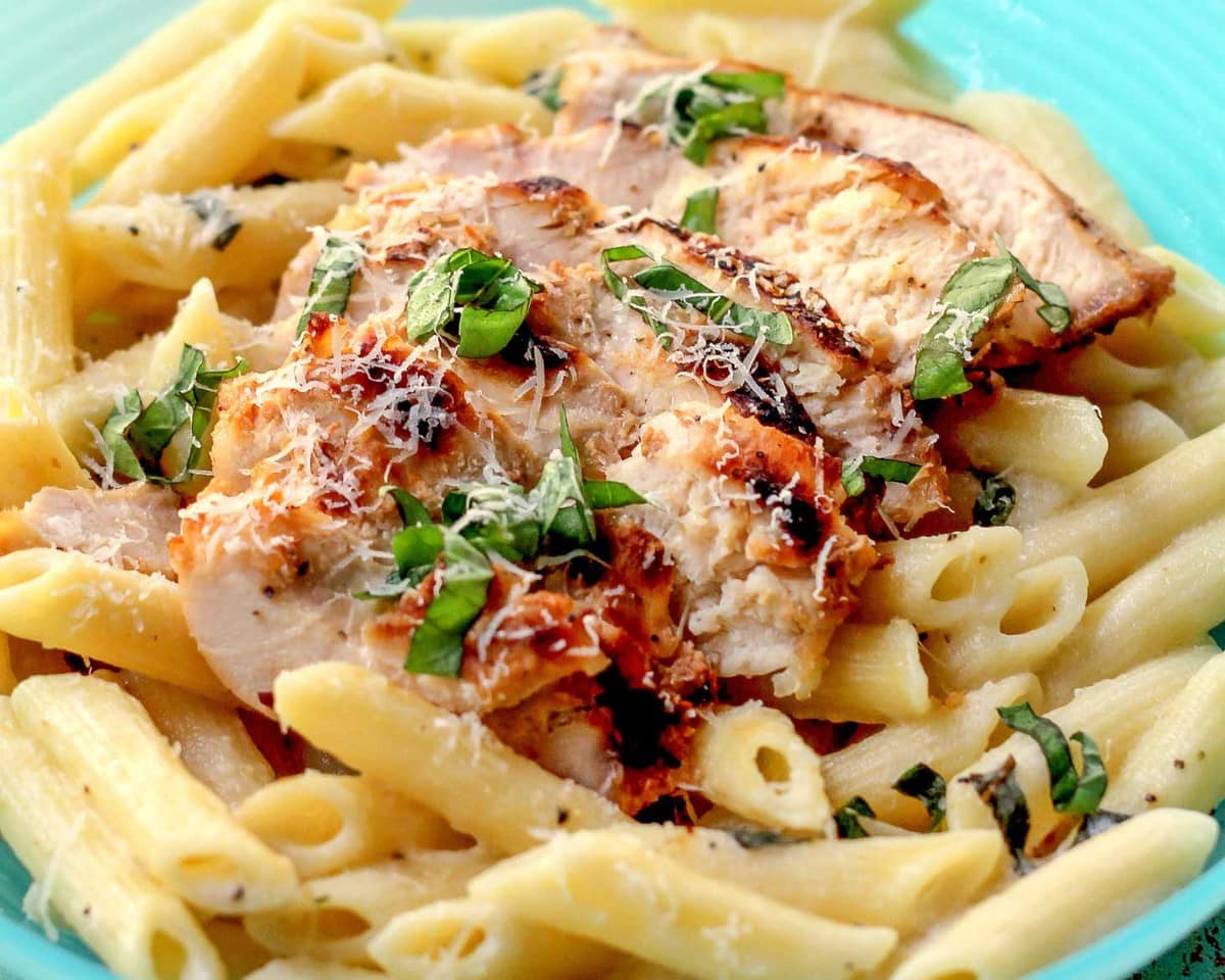 Penne Pasta Recipes - Lemon chicken pasta topped with fresh basil on a bright blue plate.