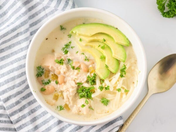 White chicken chili recipe in bowl with avocados on top.