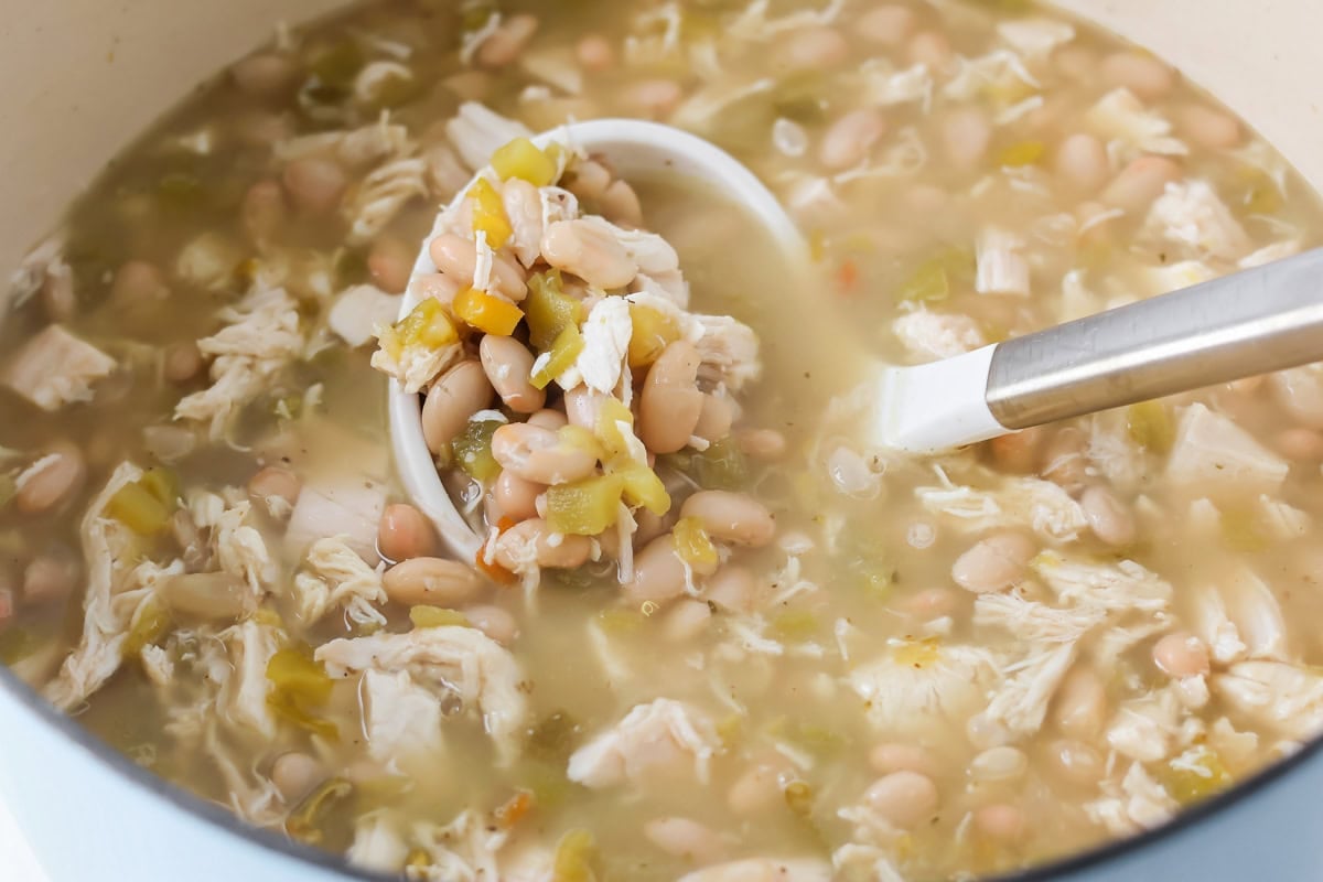White chicken chili ingredients being mixed in pot.