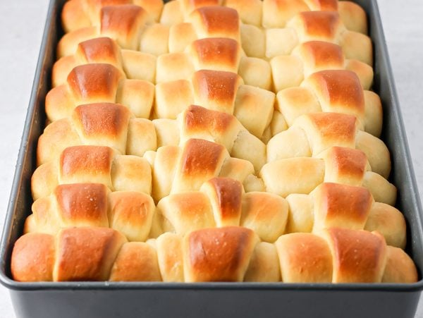 Homemade Dinner rolls baked and buttered in baking sheet.