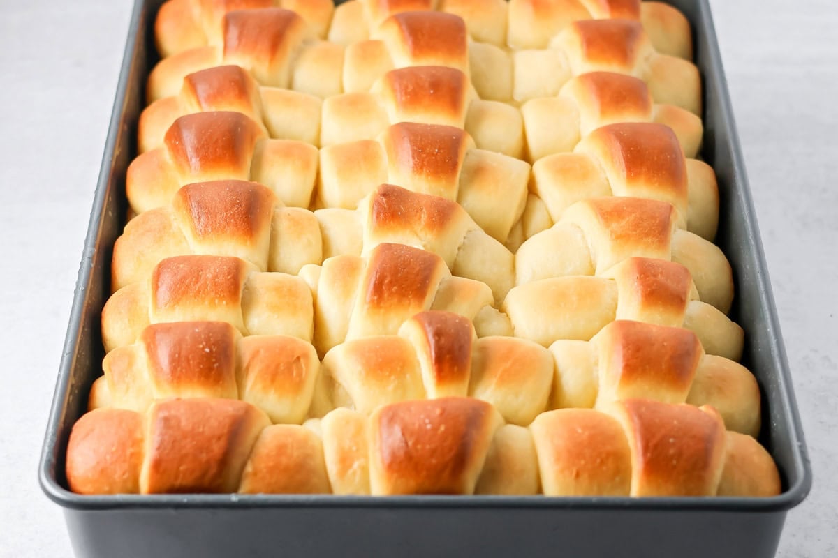 Homemade Dinner rolls baked and buttered in baking sheet.