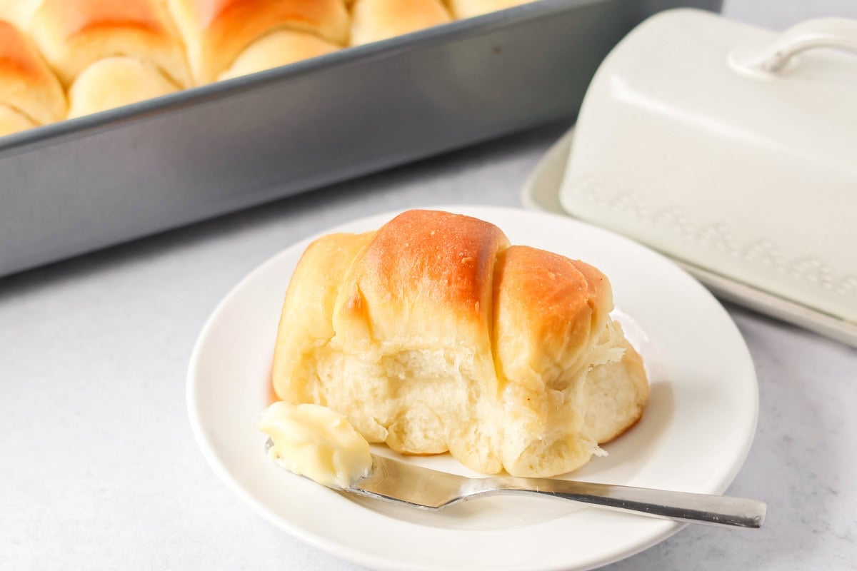 Homemade dinner roll on plate with butter.