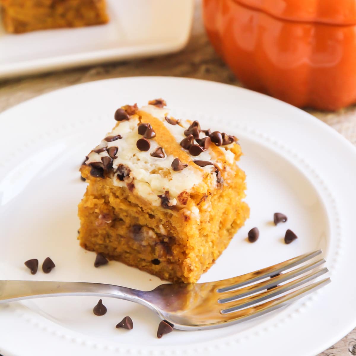 Dessert Bar Recipes - Pumpkin Cream Cheese Bars topped with mini chocolate chips on a white plate. 