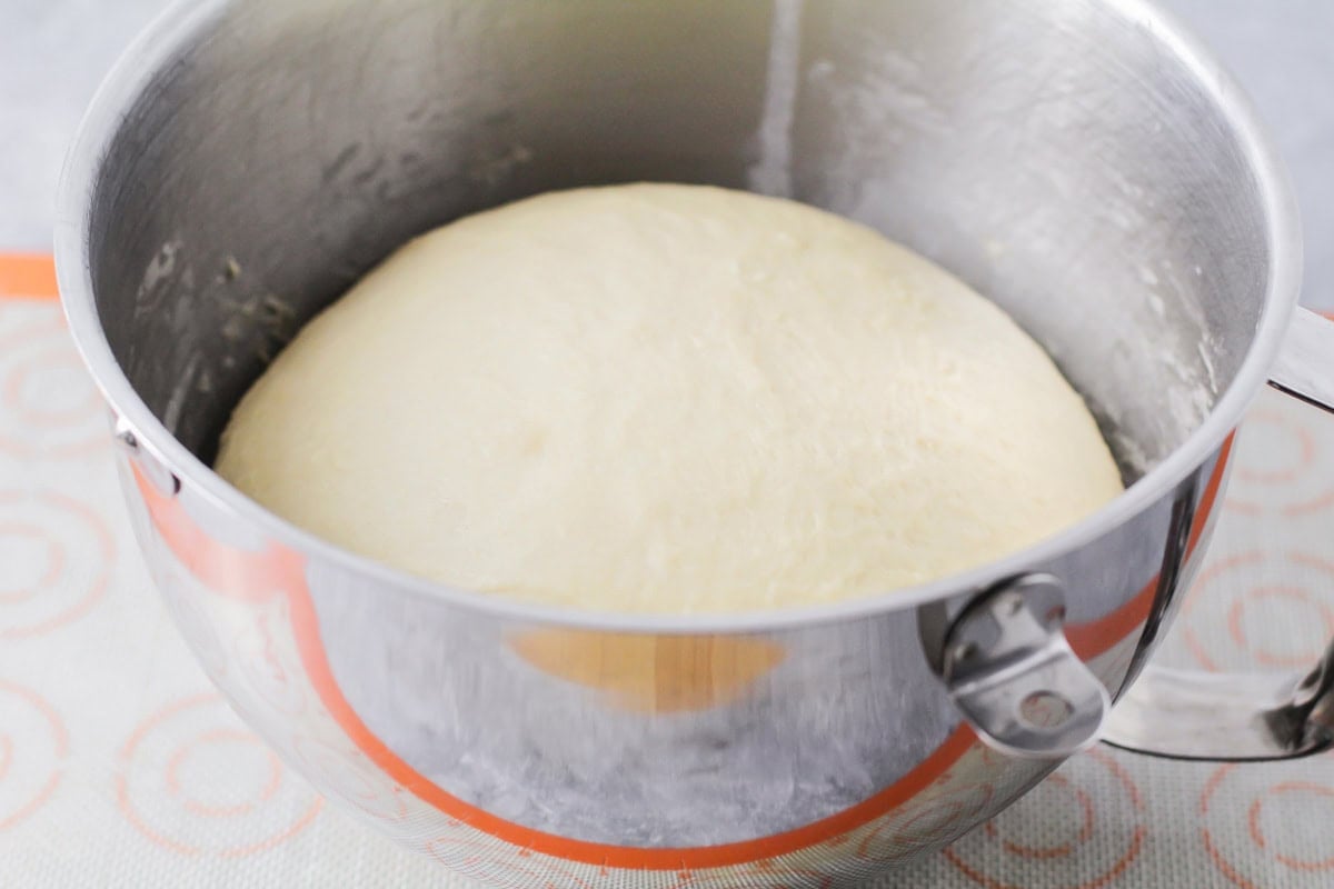 Risen yeast dinner rolls dough in mixer bowl.