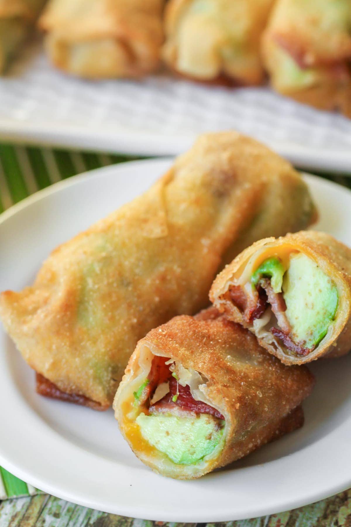 Avocado Bacon Egg Rolls fried and stacked on a white plate