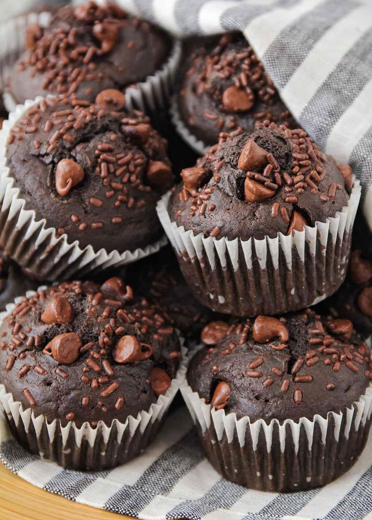 Chocolate muffins piled on a dish towel.