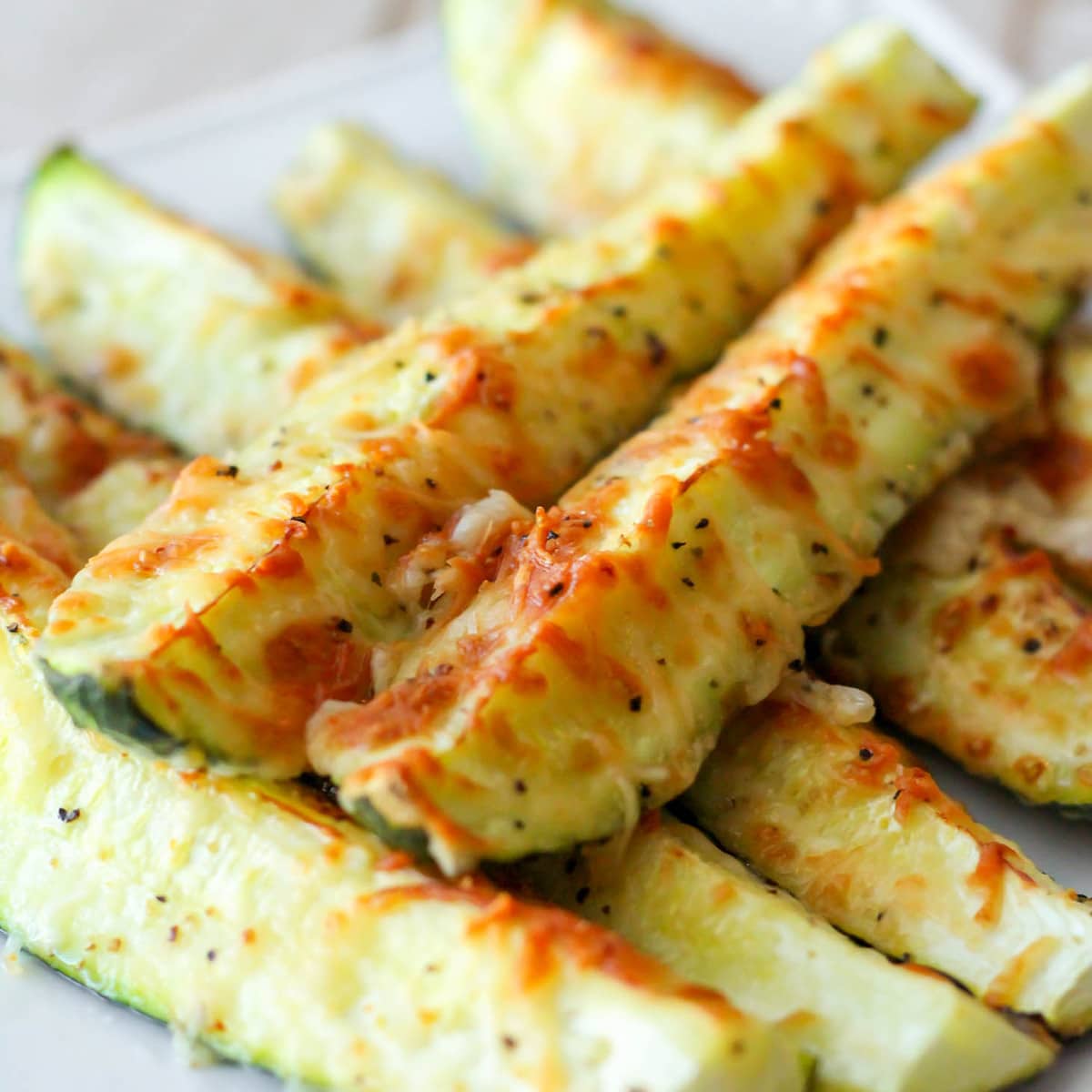 Easy side dishes - parmesan crusted zucchini piled on a white plate.