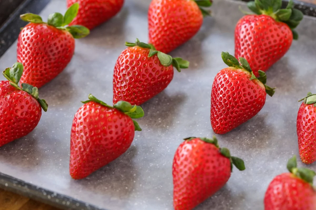 Strawberries on parchment lined baking sheet.