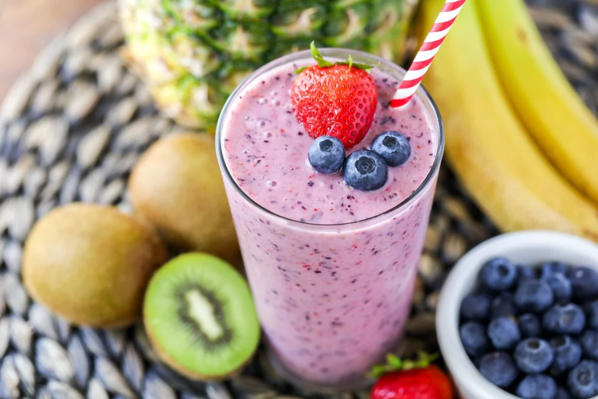Close up image of our go-to fruit smoothie recipe with fruit all around.