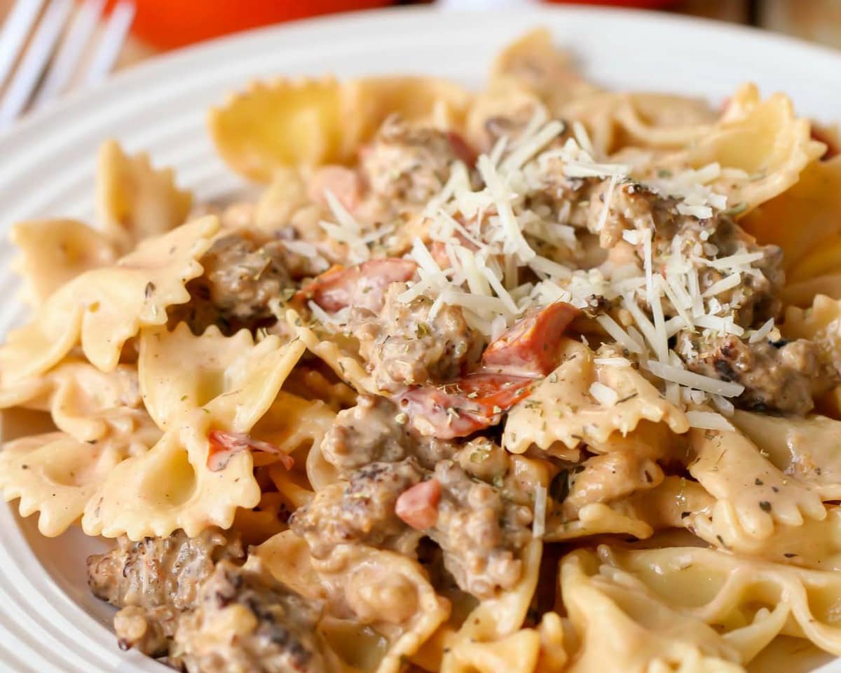 Valentines Dinner Ideas - Italian Sausage Pasta garnished with grated parmesan cheese on a white plate. 