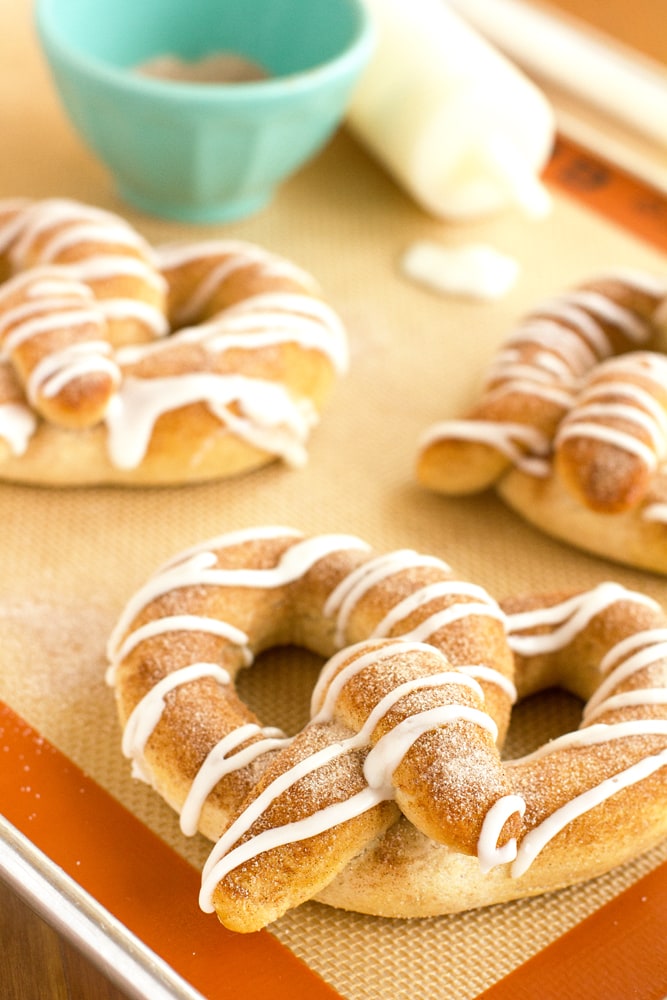 large soft cinnamon pretzels with vanilla glaze on a baking sheet